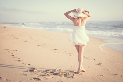 A woman walking on the beach during the day
